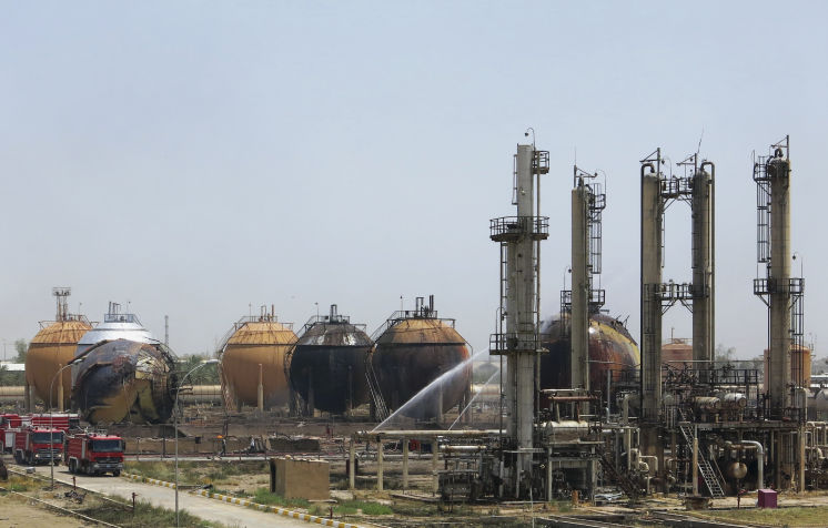 Iraqi firefighters try to extinguish a fire at a natural gas plant in Taji 12 miles north of Baghdad in Iraq on Sunday. The Islamic State group launched a coordinated assault Sunday on a natural gas plant north of the capital that killed more than a doze