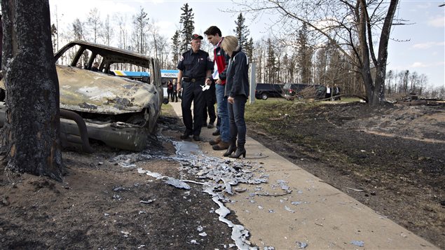 Fort Mc Murray Fire Chief Darby Allen left to right Prime Minister Justin Trudeau and Alberta Premier Rachel Notley look over a burnt out car during a visit to Fort McMurray Alta. on Friday