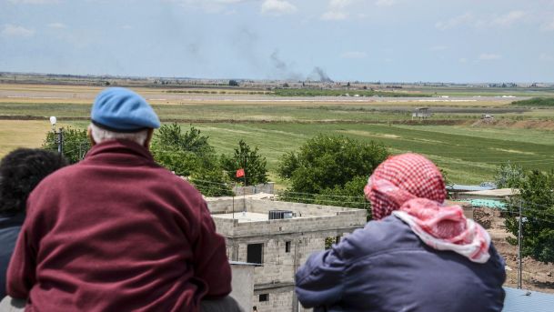 People look on as planes carry out bombing nearby in Kilis Turkey