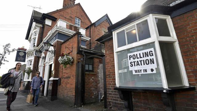 People walk past a pub being used as a polling station in west London Britain on Thursday