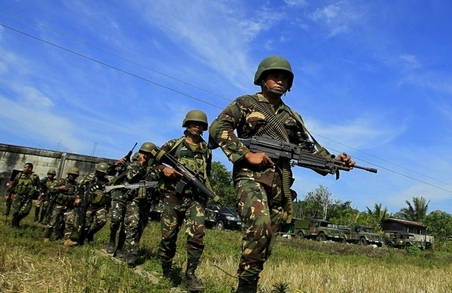 Philippine soldiers march on a rice field as they end an operation against Islamic Militants