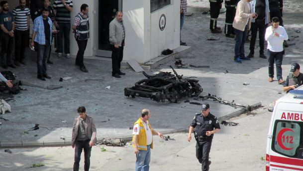 Security and forensic officials and medics investigate around the remains of a car after an explosion outside a police station in Gaziantep Turkey