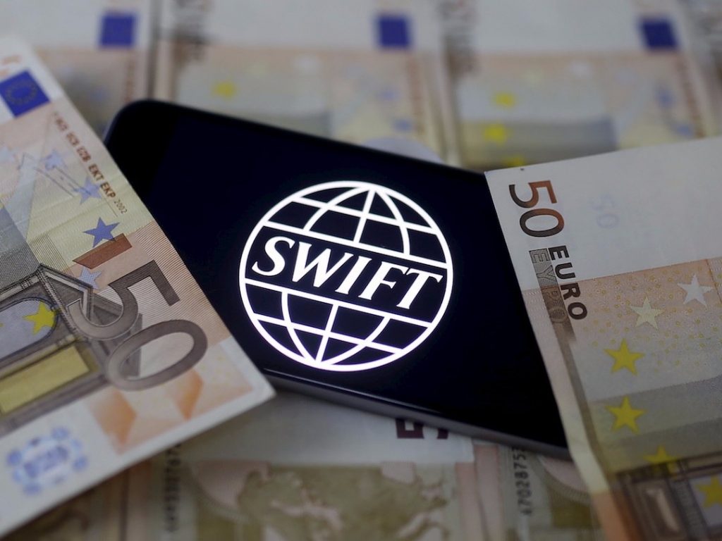 Swift code bank logo is displayed on an iPhone 6s on top of Euro banknotes in this