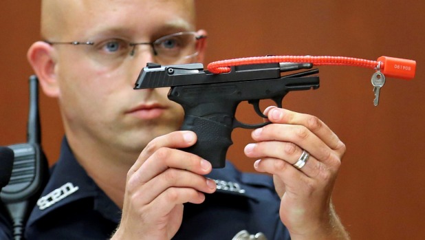 Police officer Timothy Smith holds up the gun that was used to kill Trayvon Martin during George Zimmerman's murder