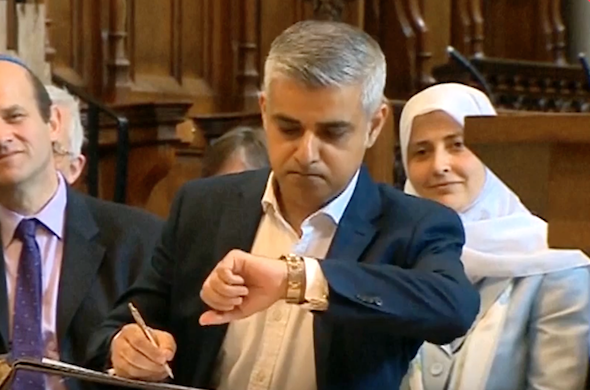 Sadiq Khan checks the time as he signs the document officially declaring him mayor of London