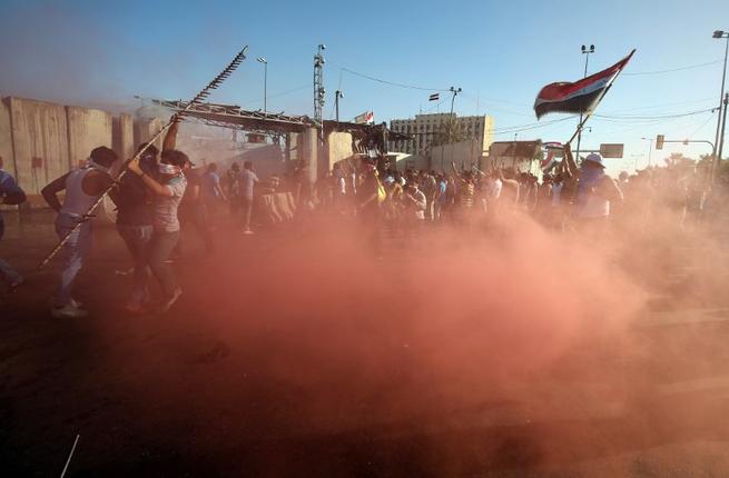 Sadrist protesters outside of Baghdad's Green Zone react to canisters of tear gas