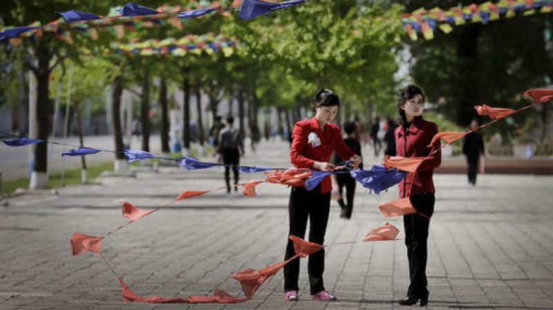 North Korean women tie flags as they decorate the streets in downtown Pyongyang North Korea Saturday