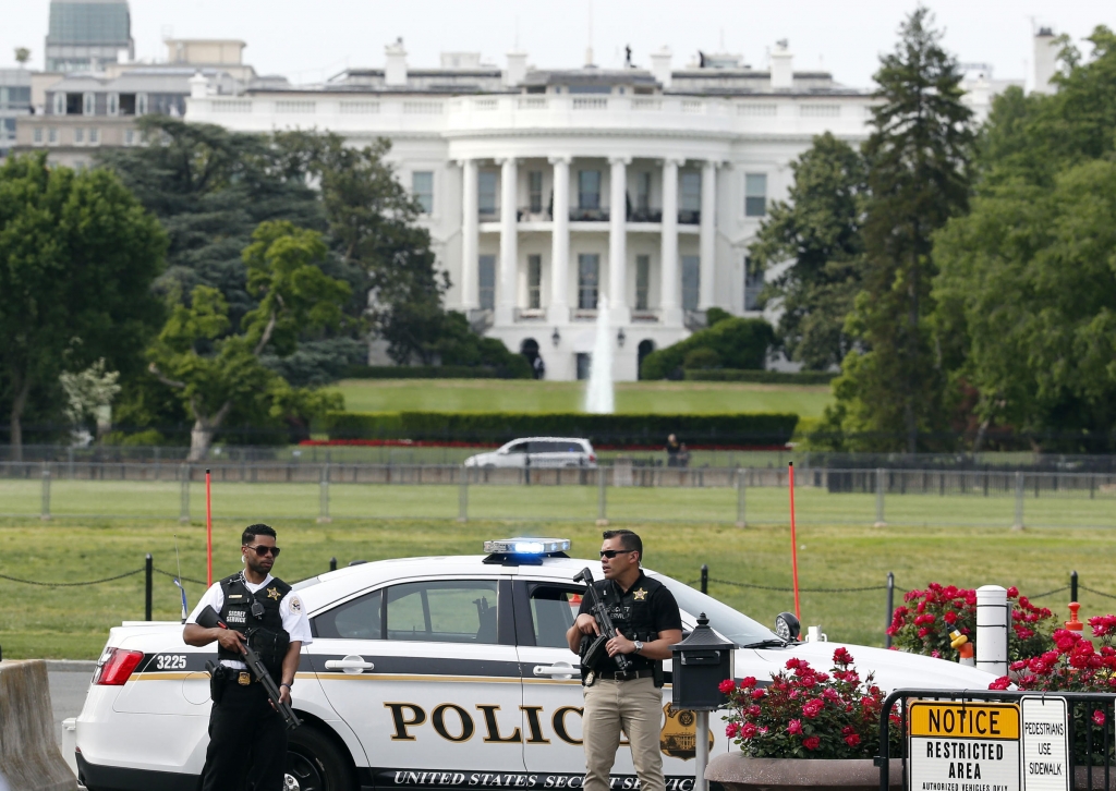 Law enforcement personnel stand south of the White House on Constitution Ave. in Washington D.C. on Friday. The White House was placed on a security alert after a Secret Service officer shot a man brandishing a firearm near a security checkpoint on