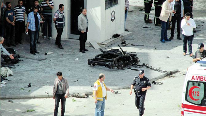 Security and forensic officials investigate around the remains of a car after an explosion outside a police station in Turkey. Pic  AFP