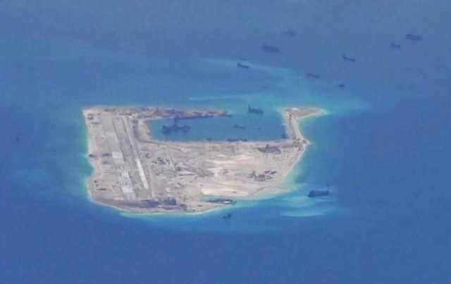 Chinese dredging vessels are purportedly seen in the waters around Fiery Cross Reef in the disputed Spratly Islands in this still image from video provided by the US Navy