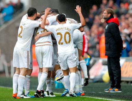 Swansea's Jack Cork celebrates scoring their second goal with team mates as Liverpool manager Juergen Klopp looks