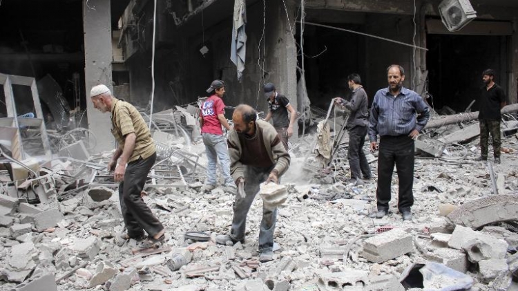 People stand amid the rubble of buildings following reported air strikes by Syrian regime forces