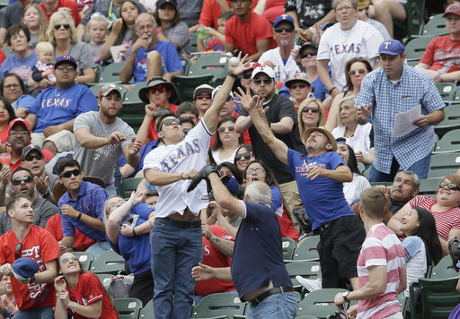 Fans try an catch a foul ball hit into the stands by Toronto Blue Jays&apos Justin Smoak during the second inning of a baseball game against the Texas Rangers in Arlington Texas Sunday