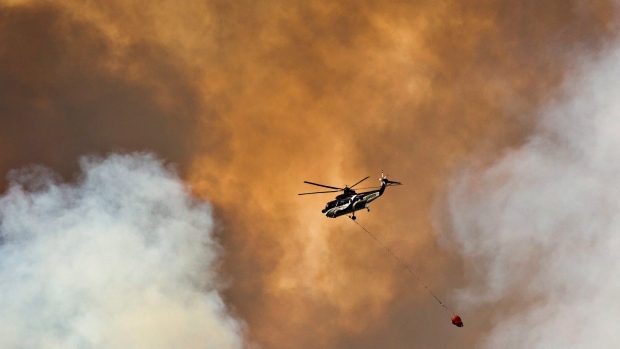 A helicopter battles a wildfire in Fort McMurray Alta. on Wednesday. Prime Minister Justin Trudeau said Thursday that Ottawa will match donations to the Red Cross to help those affected by the wildfire