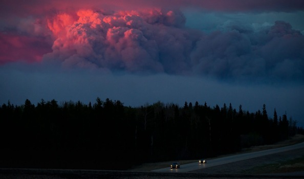 The setting sun illuminates a huge plume of smoke from wildfires burning in the distance rising over Fort McMurray Alberta