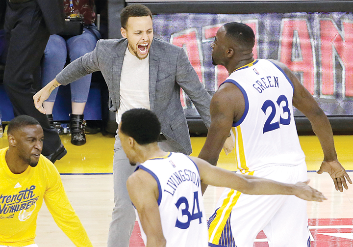 Injured star Stephen Curry celebrates with teammates Draymond Green and Shaun Livingston during the Golden State Warriors’ 110-99 victory over the Portland Trail Blazers that gave the defending champions a 2-0 lead in their NBA Western Conference