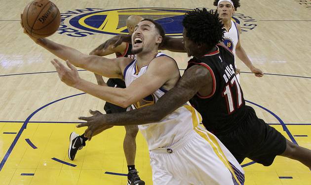 Golden State Warriors guard Klay Thompson front left is fouled by Portland Trail Blazers center Ed Davis while scoring during the second half in Game 1 of a second-round NBA basketball playoff series in Oakland Calif. Sunday