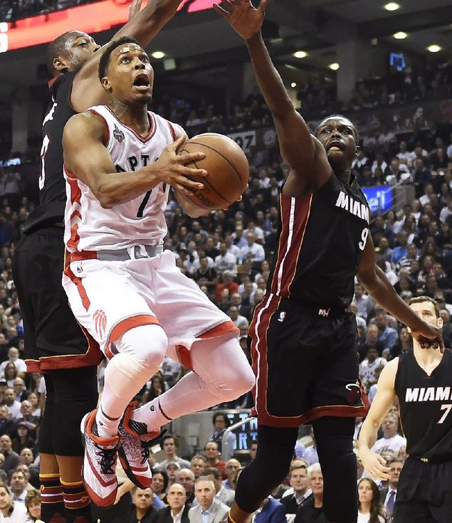 Toronto’s Kyle Lowry drives to the basket as Miami’s Luol Deng and Dwyane Wade defend during the first half of the Raptors’ 99-91 victo