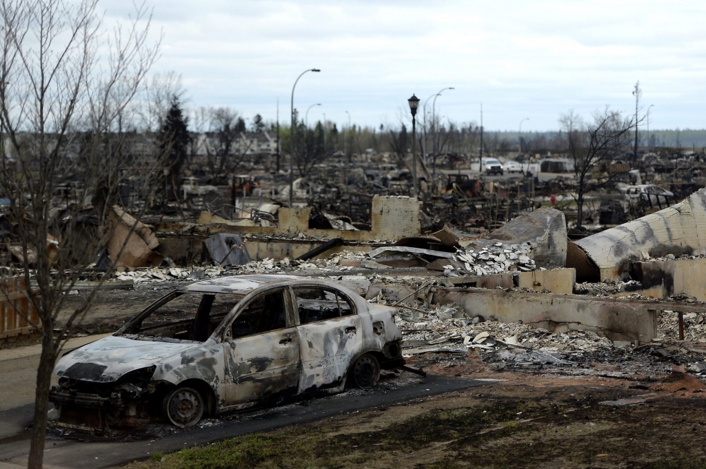 A burned out car and houses are viewed in the Beacon Hill neighborhood during a media tour of the fire-damaged city of Fort McMurray Alberta Monday