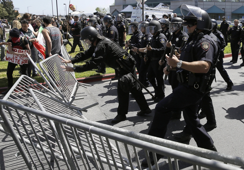 Police officers push down barricades used by a group protesting Republican presidential candidate Donald Trump outside of the Hyatt Regency hotel during the California Republican Party 2016 convention in Burlingame Calif. Friday