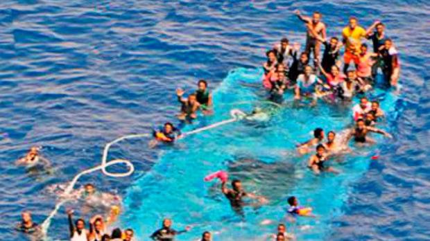 Migrants are seen on a partially submerged boat before rescued by Spanish fregate