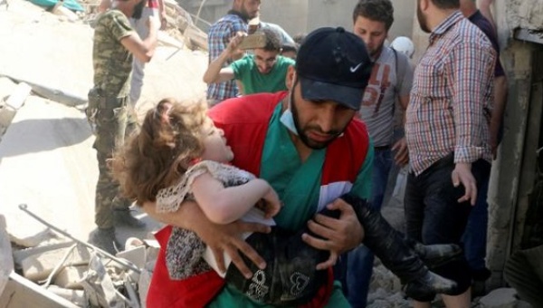 A civil defence member carries a child that survived from under the rubble at a site hit by airstrikes in the rebel held area of Old Aleppo Syria