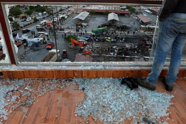 A man stands on shattered glass overlooking a damaged bus station after explosions hit it in the Syrian city of Jableh