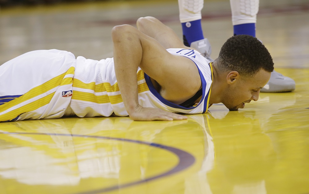 Golden State Warriors&#039 Stephen Curry goes down with an injury during Game 1 of a first-round NBA basketball playoff series against the Houston Rockets Saturday