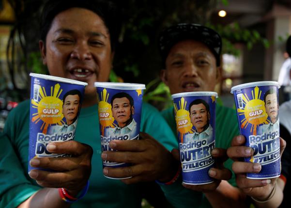 Mall parking attendants and supporters of presidential candidate Rodrigo Duterte for the May 9 election pose with'Big Gulp soda cups they bought from convenience store 7-Eleven in Paranaque Metro Manila Philippines