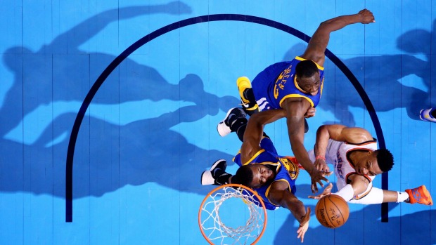 Under the bright lights Oklahoma City star Russell Westbrook shoots against Draymond Green and Festus Ezeli in the