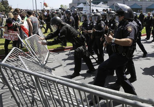 Police officers push down barricades used by a group protesting Republican presidential candidate Donald Trump outside of the Hyatt Regency hotel during the California Republican Party 2016 convention in Burlingame Calif. Friday