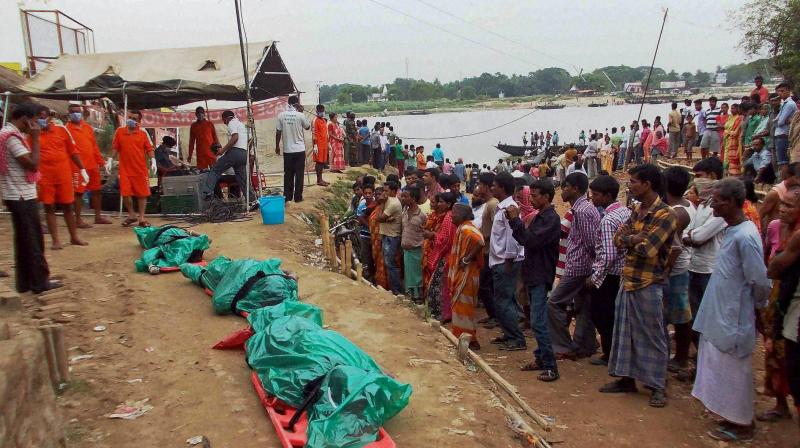 People gather near the bodies recovered after the search operation following the sinking of a country boat in Kalna in Burdwan district on Monday