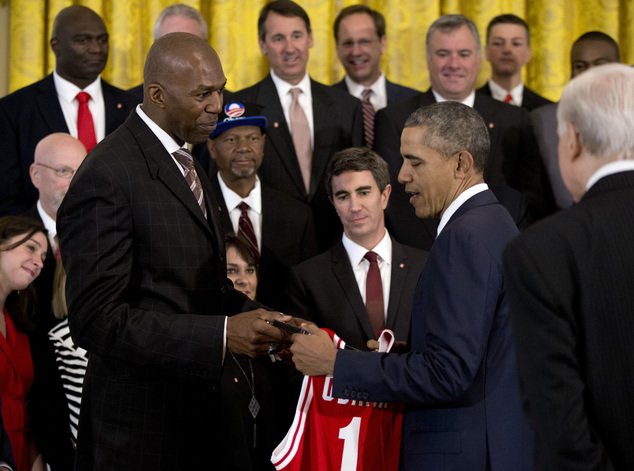 Former North Carolina State Wolfpack basketball player retired NBA player Thurl Bailey gives President Barack Obama a jersey and gift as other members