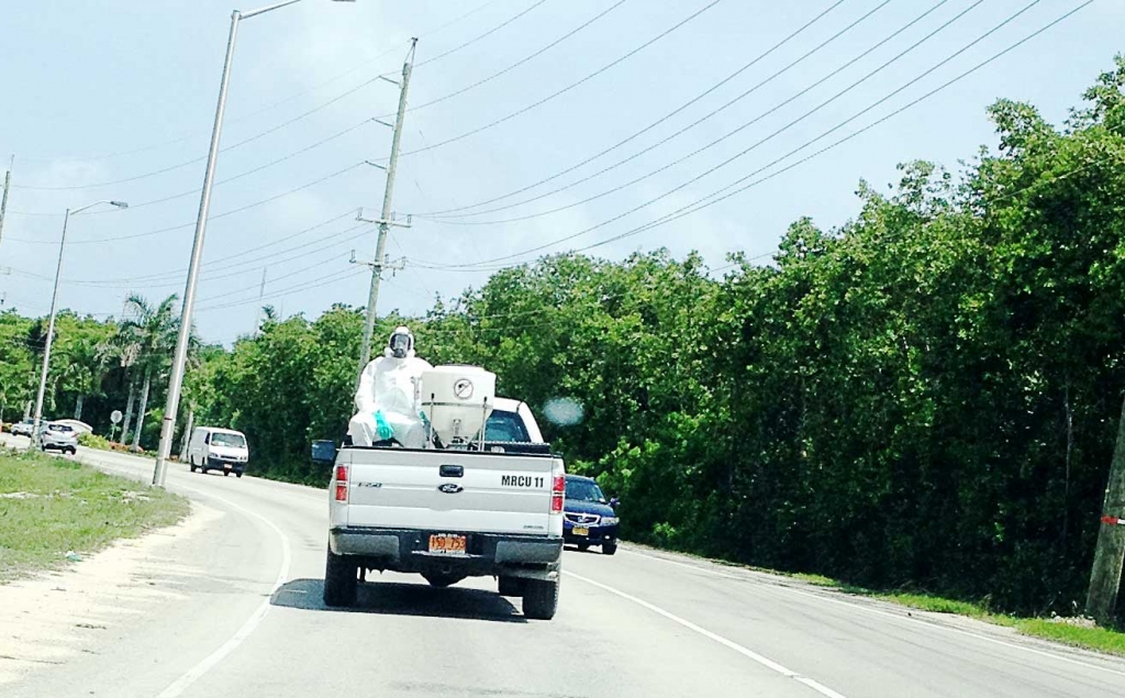 A Mosquito Research and Control Unit truck transports a fogging machine and a suited mosquito control officer