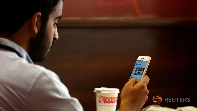 A Saudi man explores social media on his mobile device as he sits at a cafe in Riyadh Saudi Arabia