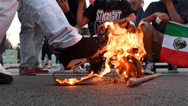 A Trump hat burns during the protest in San Jose