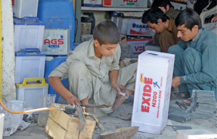 A child repairs a battery at his workplace at Shoba Bazaar Peshawar on the eve of World Day Against Child Labour