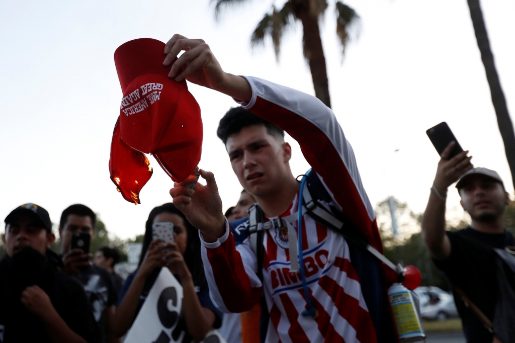 A demonstrator burns a hat in protest of Donald Trump outside a campaign rally in San Jose California