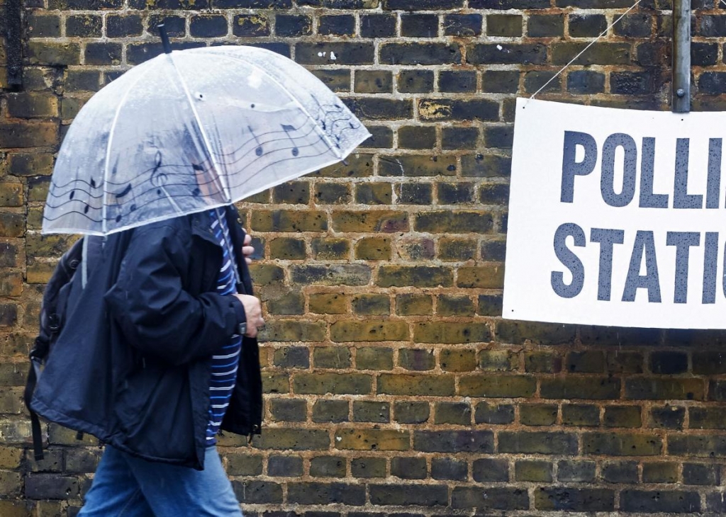 542344304-man-shelters-from-the-rain-as-he-arrives-at-a-polling_1