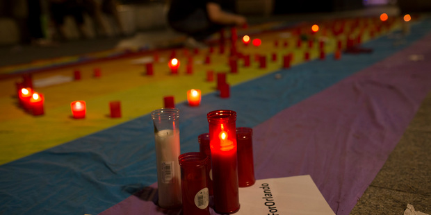 A man lights candles placed on top of a big rainbow flag in solidarity with Florida's shooting attack victims in Madrid Spain