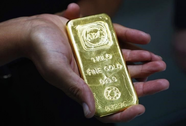 A woman holds a one-kilogramme gold bar at the headquarters of the Australian Bullion Company in Sydney