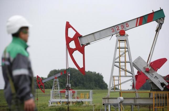 A worker looks at a pump jack at an oil field Buzovyazovskoye owned by Bashneft company north from Ufa Bashkortostan Russia