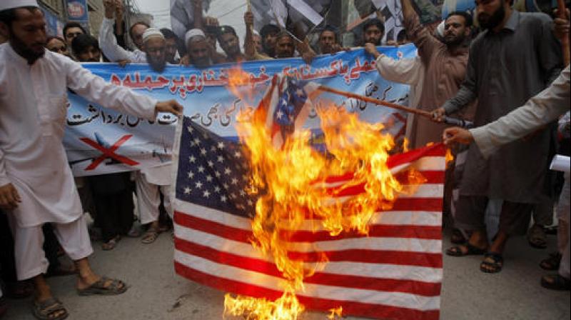 Supporters of Pakistani religious group Jamaat-ud Dawa burn representation of an American flag during a protest rally to condemn the US drone strike in Pakistani territory which killed Taliban leader Mullah Mansour