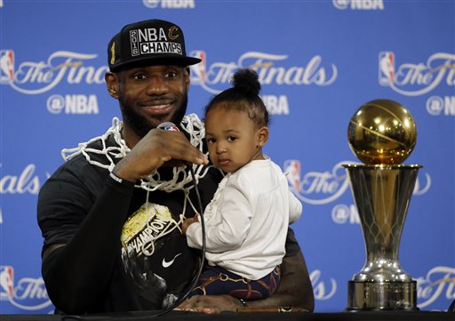 Cleveland Cavaliers Le Bron James answers questions as he holds his daughter Zhuri during a post-game press conference after Game 7 of basketball's NBA Finals Sunday