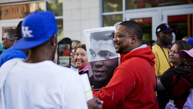 Members of the public stand in line with a newspaper image of Muhammad Ali while waiting for the box office to open for tickets to Ali's memorial service Friday at the KFC Yum! Center Wednesday