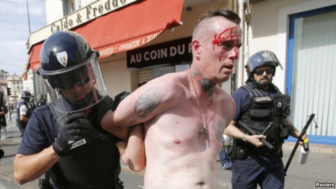 An injured man is led away by French police in Marseille following clashes between Russia and England supporters after a 1-1 draw in Marseille on June