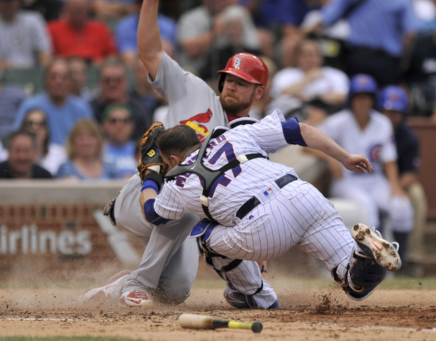 Chicago Cubs catcher Miguel Montero attempts to apply the tag as St. Louis Cardinals Brandon Moss back slides into home plate safely on a Yadier Molin