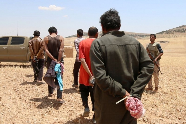 Men who the Democratic Forces of Syria fighters claimed were Islamic State fighters walk as they are taken prisoners after SDF advanced in the southern rural area of Manbij in Aleppo Governorate Syria