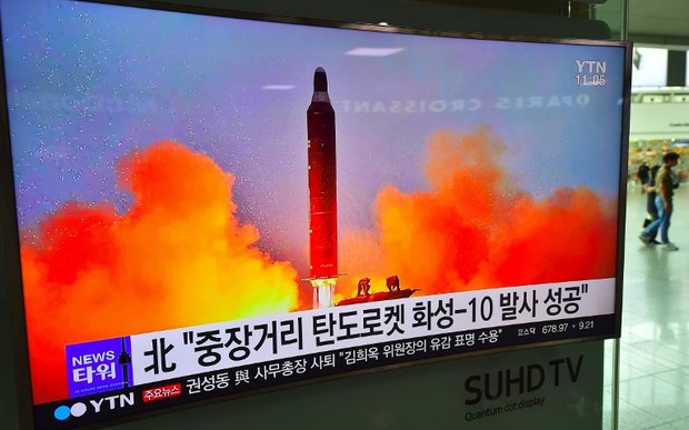 People walk past a television screen reporting news of North Korea's latest Musudan missile test at a railway station in Seoul