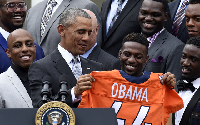 ASSOCIATED PRESS           President Barack Obama holds up a Denver Broncos team football jersey as he welcomes the Super Bowl Champions during a ceremony in the Rose Garden of the White House in Washington today